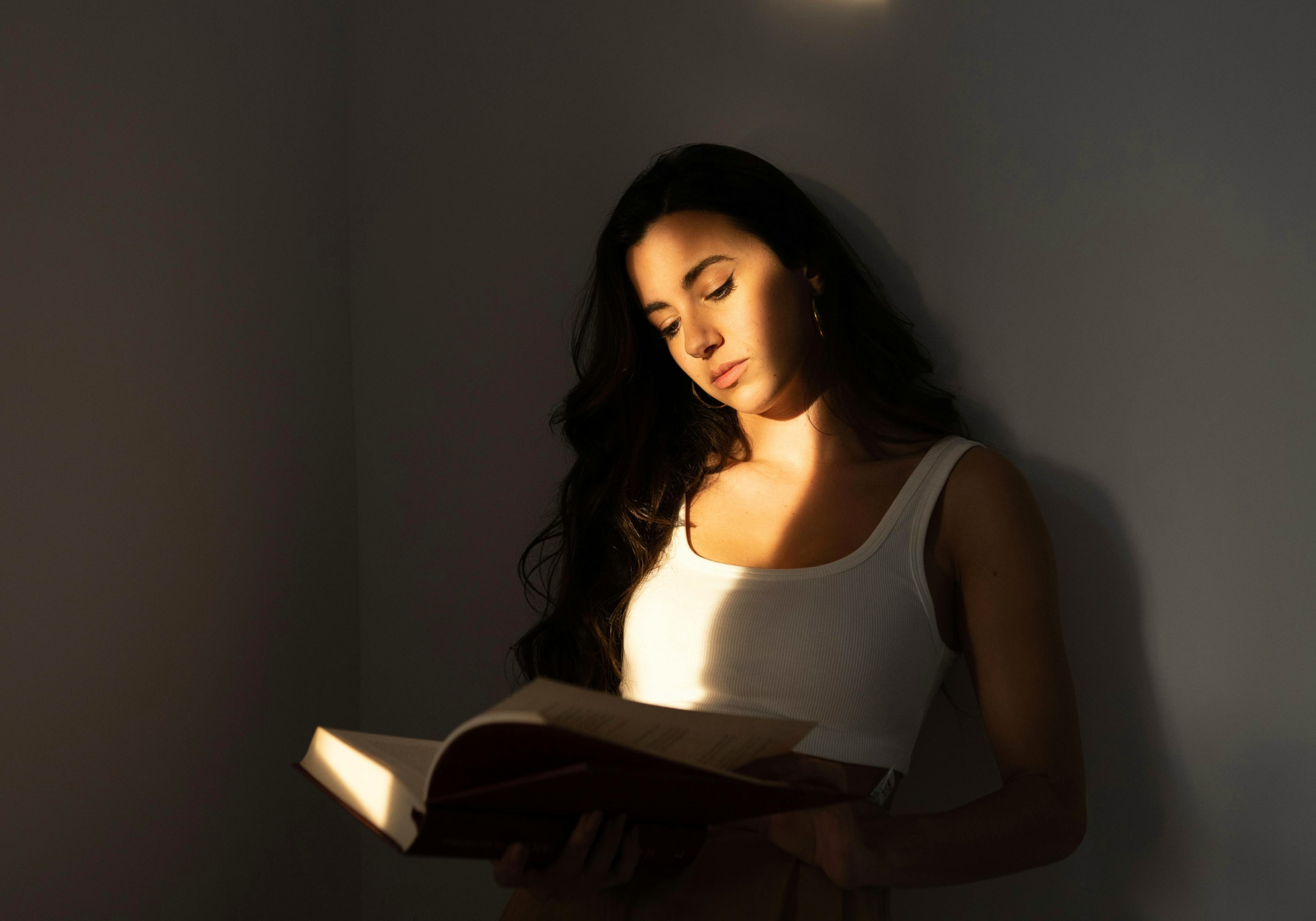 A woman reading in soft, moody light, reflecting the emotional intensity and immersive experience behind WNGSPN’s fiction-inspired collections.
