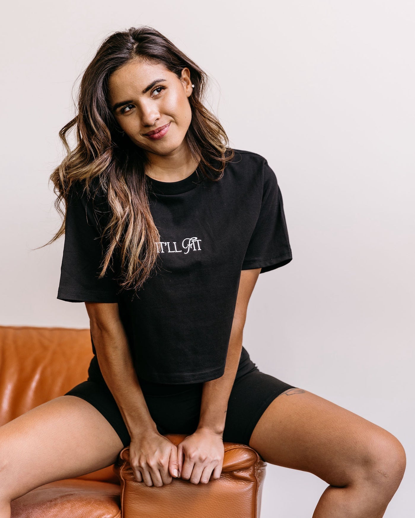 Female main character wearing a black embroidered cropped tee from the WNGSPN spicy romance inspired bookish apparel collection.