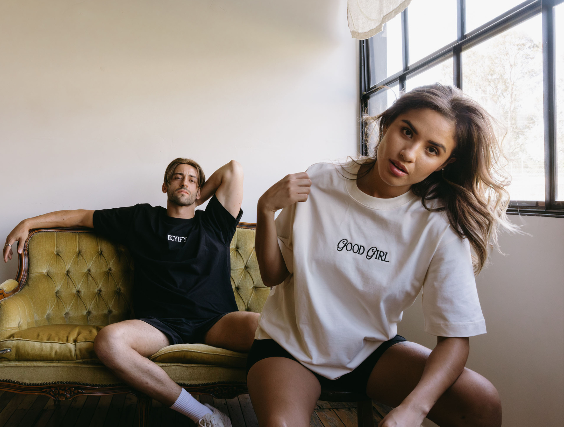 Model wearing WNGSPN “Good Girl” embroidered tee with model in background wearing “IICYIFY” tee