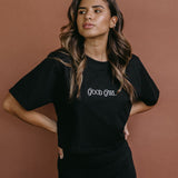 Female model wearing the black "Good Girl" cropped embroidered T-shirt by WNGSPN, styled with understated confidence.