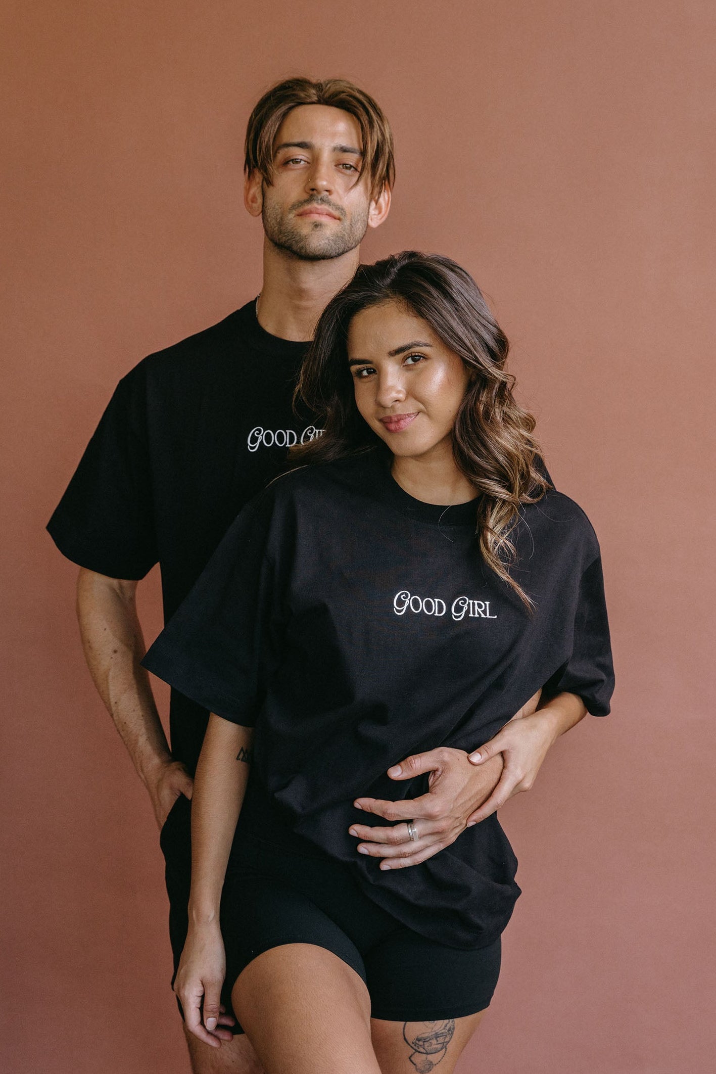Couple wearing the black "Good Girl" relaxed fit embroidered T-shirt by WNGSPN, styled as elevated romance reader apparel.