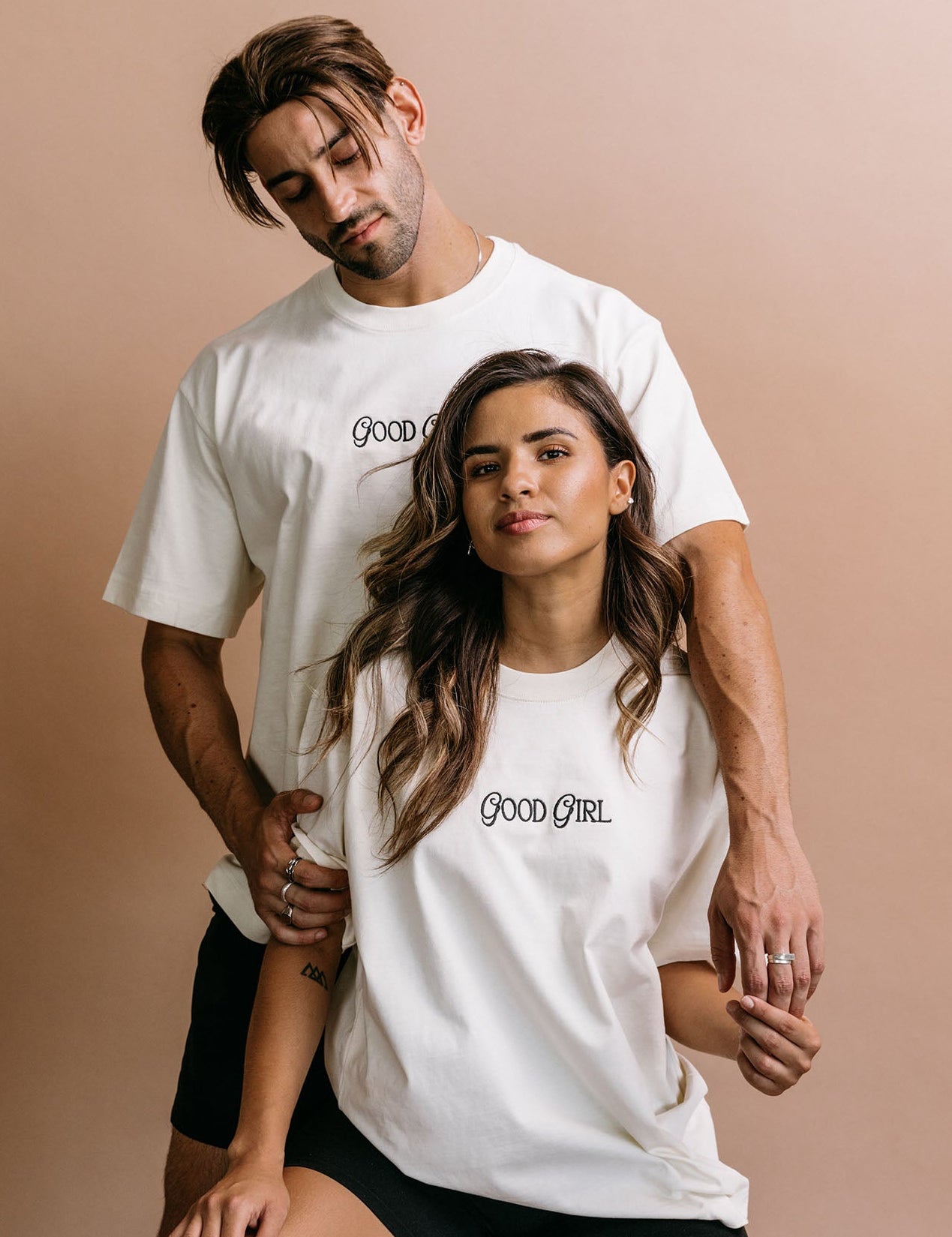 Couple wearing the ecru "Good Girl" relaxed fit embroidered T-shirt by WNGSPN, capturing a refined bookish aesthetic.
