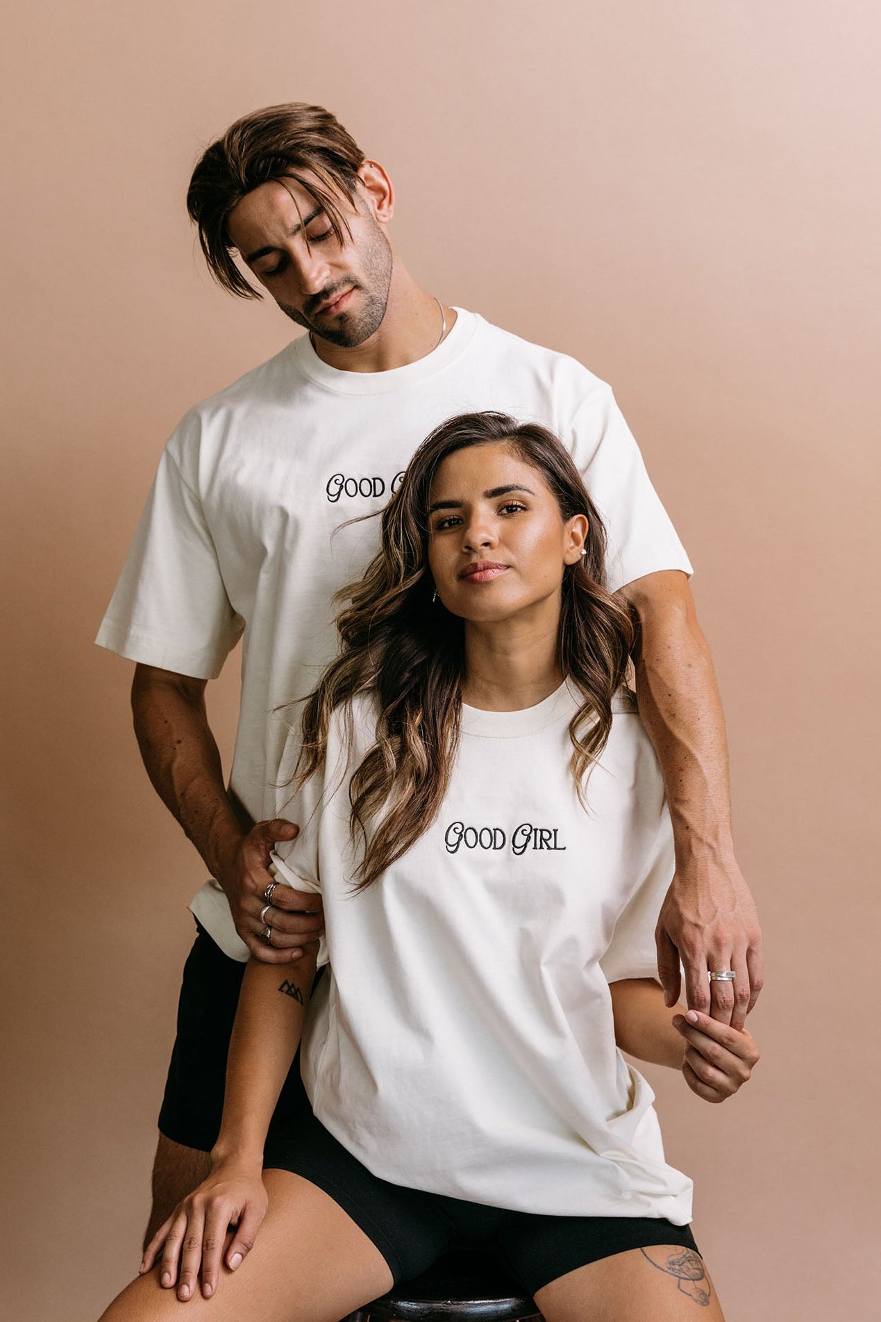 Couple wearing the ecru "Good Girl" relaxed fit embroidered T-shirt by WNGSPN, capturing a refined bookish aesthetic.