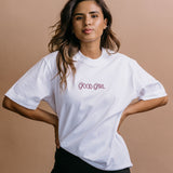 Female model wearing the white "Good Girl" relaxed fit embroidered T-shirt by WNGSPN, with a relaxed silhouette and clean lines.