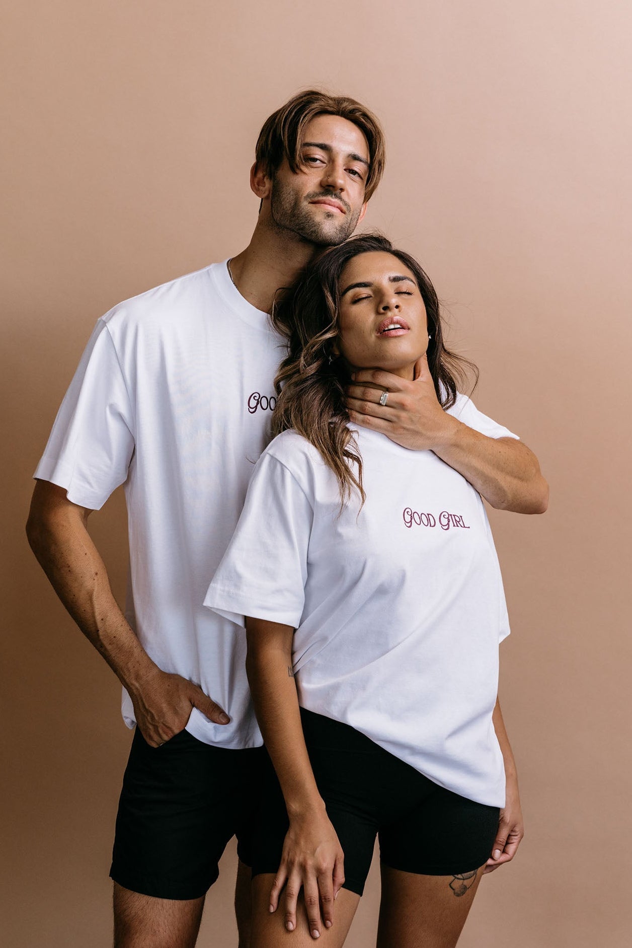Couple wearing the white "Good Girl" relaxed fit embroidered T-shirt by WNGSPN, with subtle tension and modern edge.