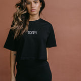 Female model wearing the black "Iicyify" cropped embroidered T-shirt by WNGSPN, styled with understated confidence.