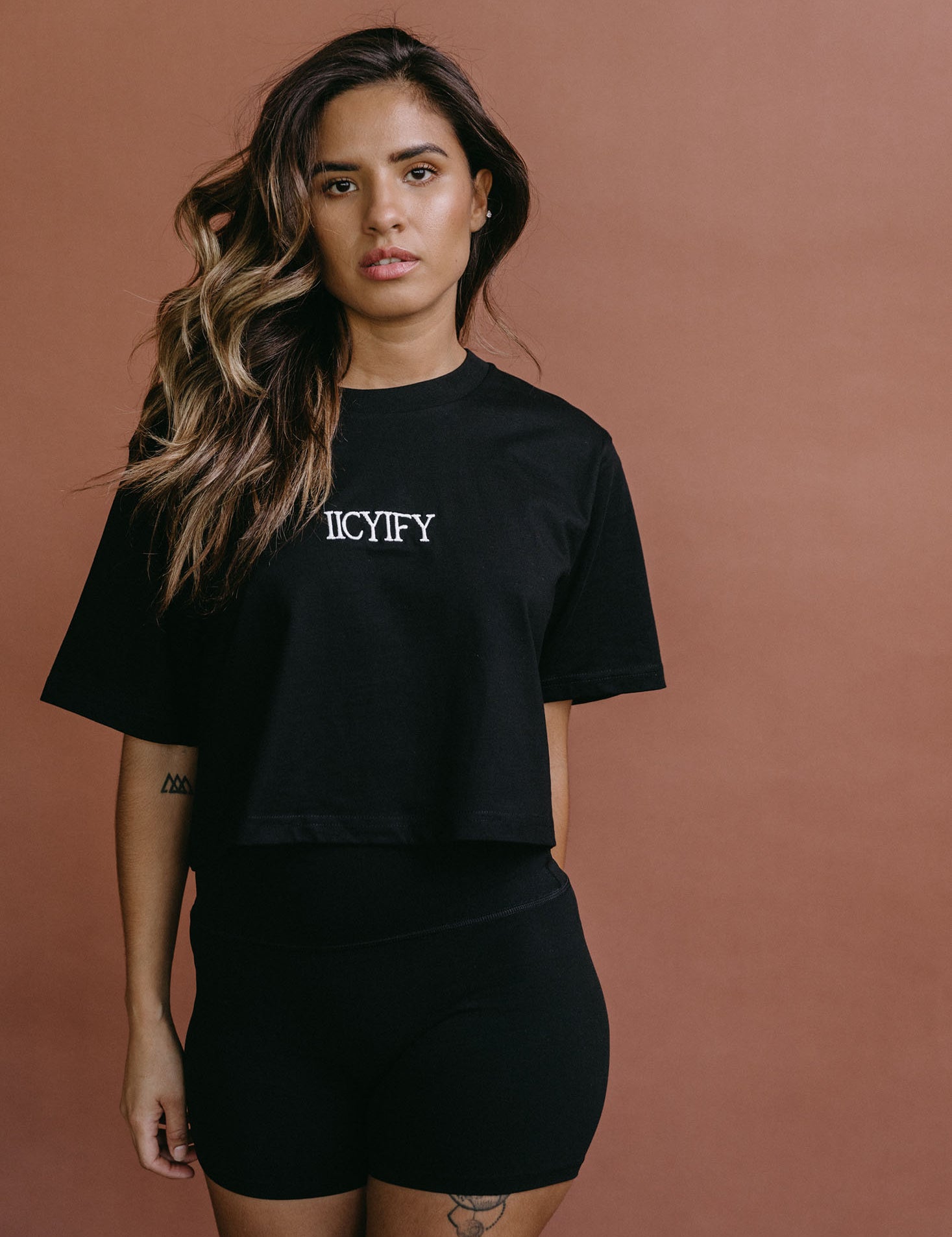 Female model wearing the black "Iicyify" cropped embroidered T-shirt by WNGSPN, styled with understated confidence.