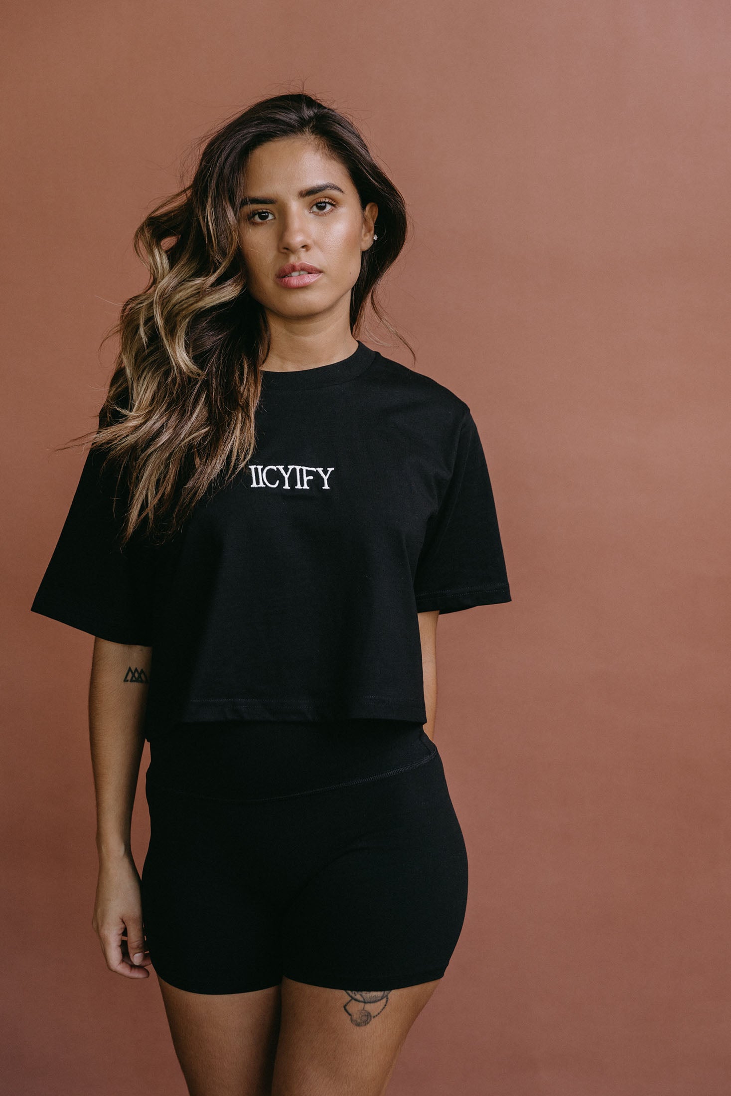 Female model wearing the black "Iicyify" cropped embroidered T-shirt by WNGSPN, styled with understated confidence.