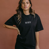 Female model wearing the black "Iicyify" relaxed fit embroidered T-shirt by WNGSPN, styled with understated confidence.