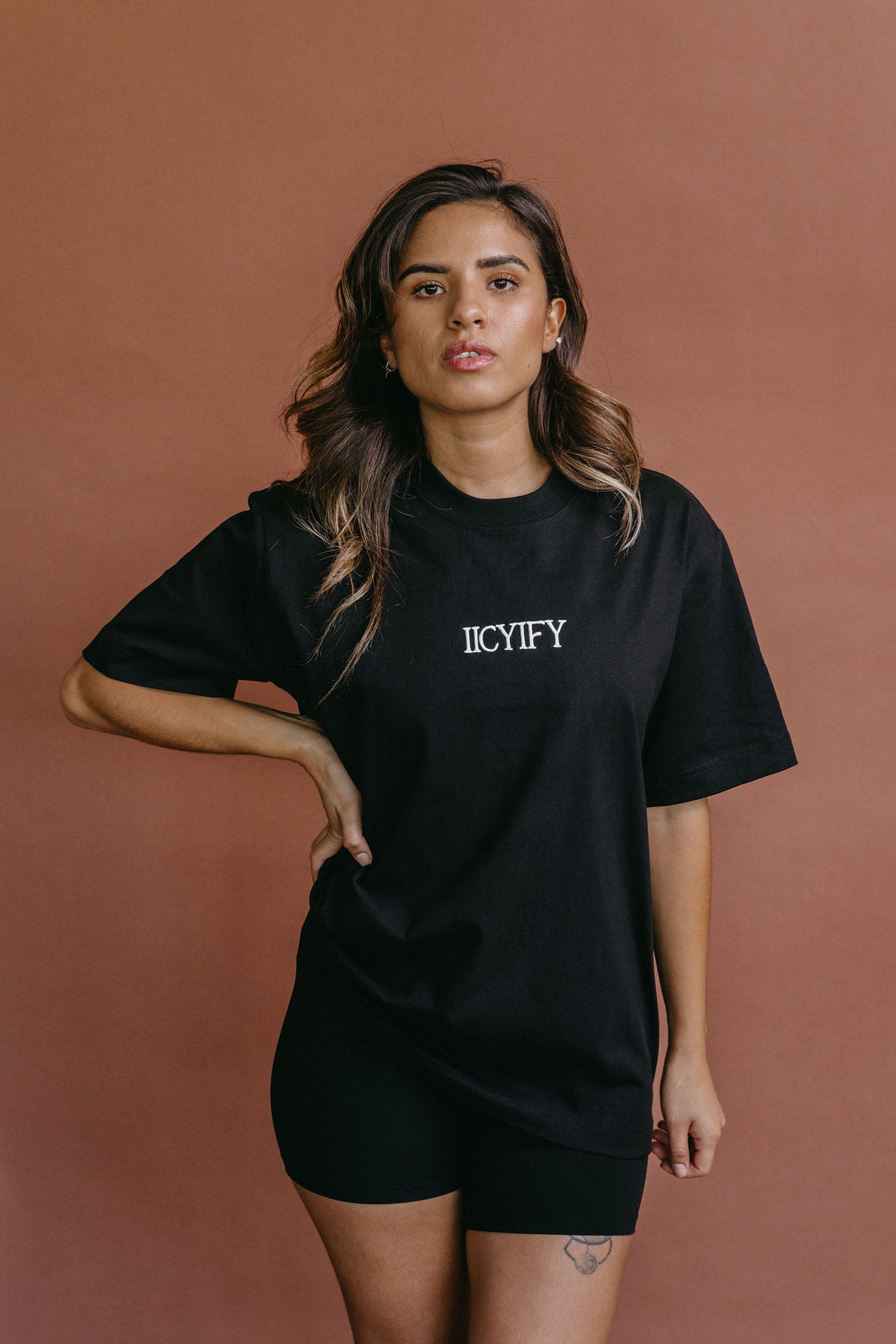 Female model wearing the black "Iicyify" relaxed fit embroidered T-shirt by WNGSPN, styled with understated confidence.
