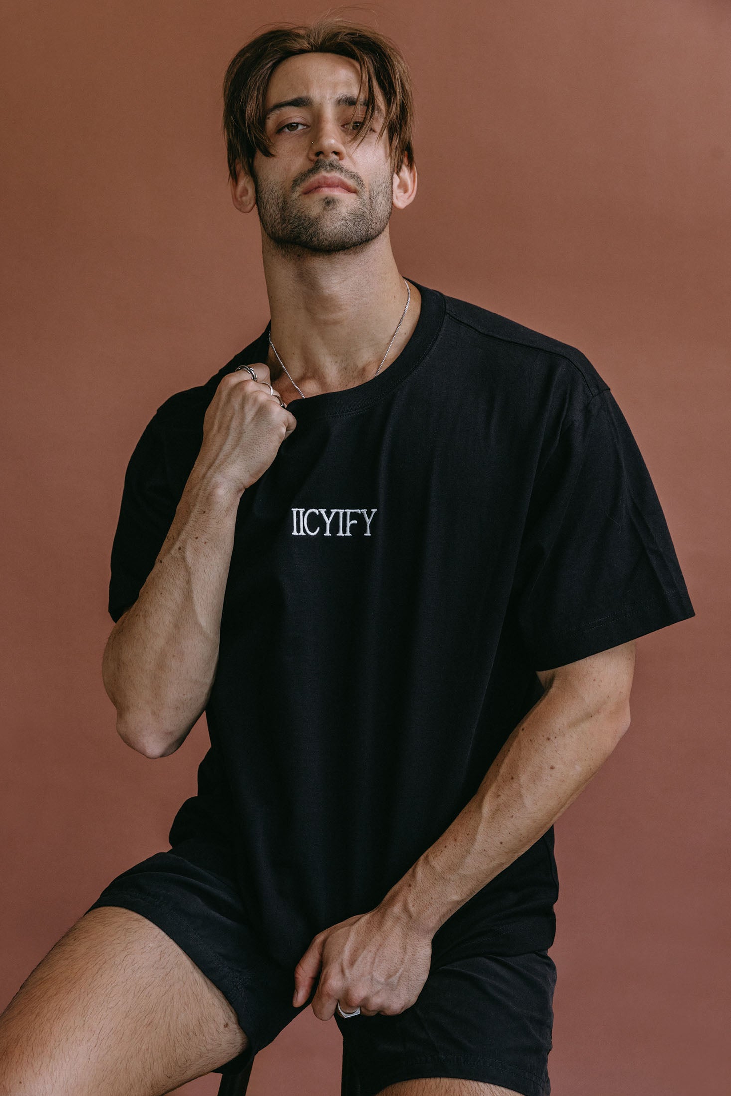 Male model wearing the black "Iicyify" relaxed fit embroidered T-shirt by WNGSPN, styled with understated confidence.