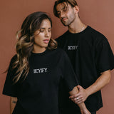 Couple wearing the black "Iicyify" relaxed fit embroidered T-shirt by WNGSPN, styled as elevated romance reader apparel.