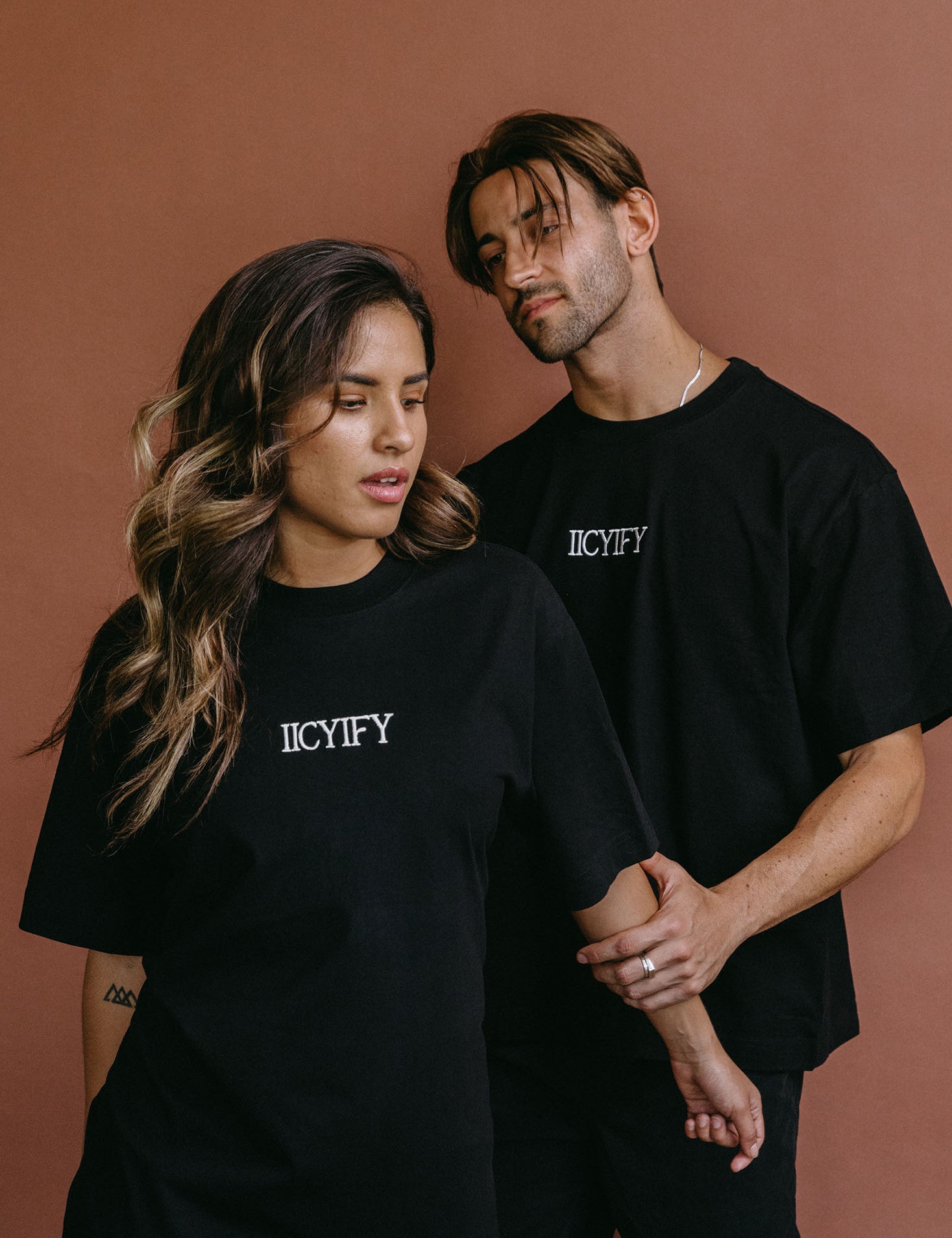 Couple wearing the black "Iicyify" relaxed fit embroidered T-shirt by WNGSPN, styled as elevated romance reader apparel.