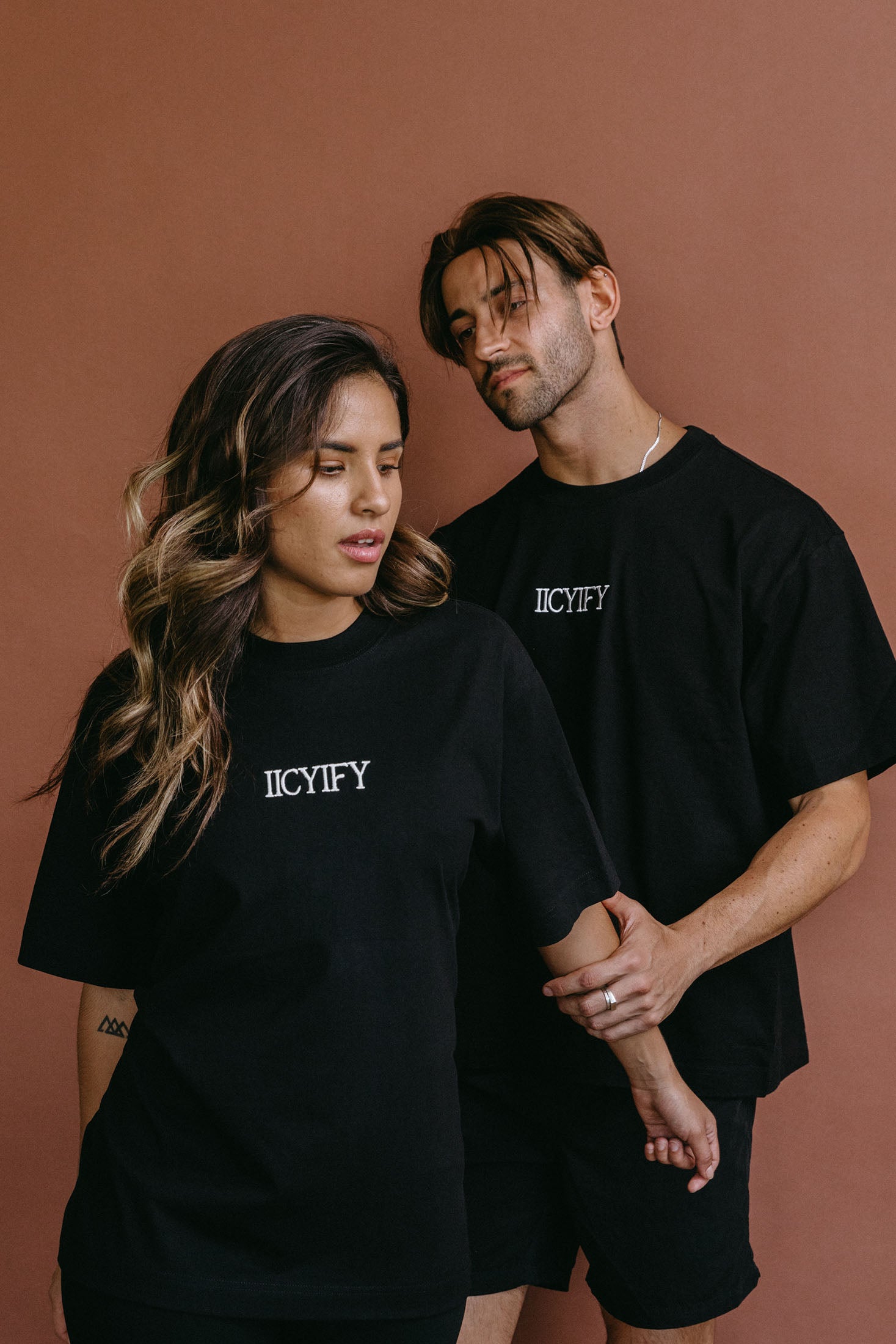 Couple wearing the black "Iicyify" relaxed fit embroidered T-shirt by WNGSPN, styled as elevated romance reader apparel.