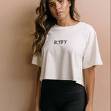 Female model wearing the ecru "Iicyify" cropped embroidered T-shirt by WNGSPN, with a relaxed silhouette and clean lines.