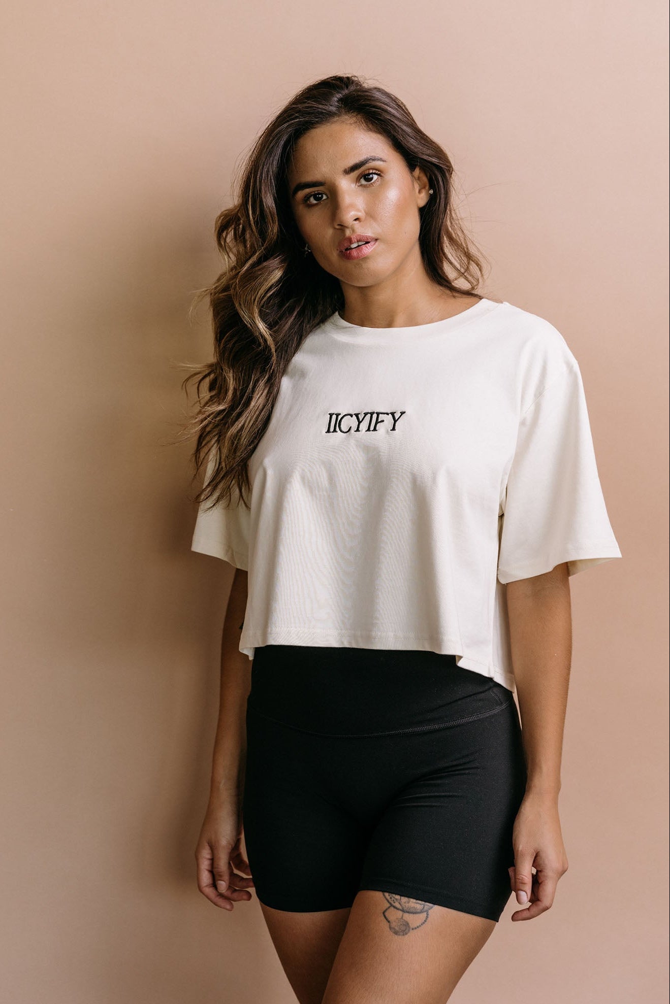Female model wearing the ecru "Iicyify" cropped embroidered T-shirt by WNGSPN, with a relaxed silhouette and clean lines.