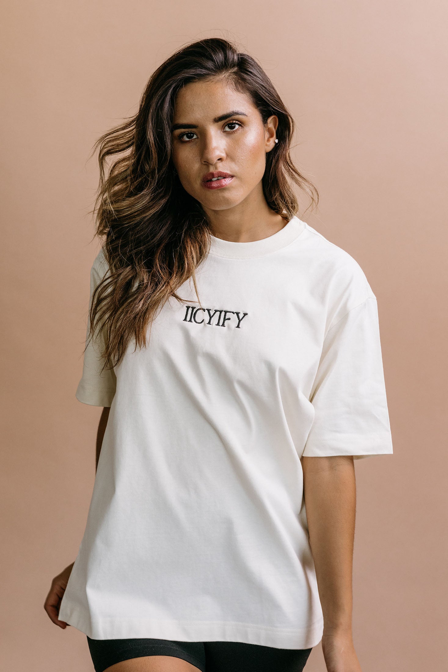 Female model wearing the ecru "Iicyify" relaxed fit embroidered T-shirt by WNGSPN, styled in a minimal, elevated aesthetic.