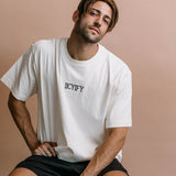 Male model wearing the ecru "Iicyify" relaxed fit embroidered T-shirt by WNGSPN, styled in a minimal, elevated aesthetic.