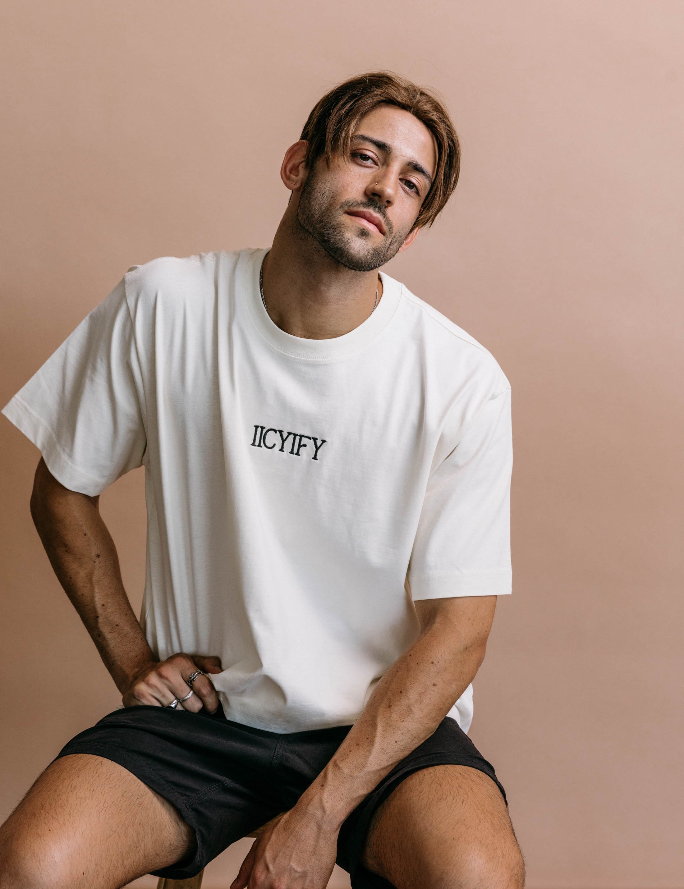 Male model wearing the ecru "Iicyify" relaxed fit embroidered T-shirt by WNGSPN, styled in a minimal, elevated aesthetic.