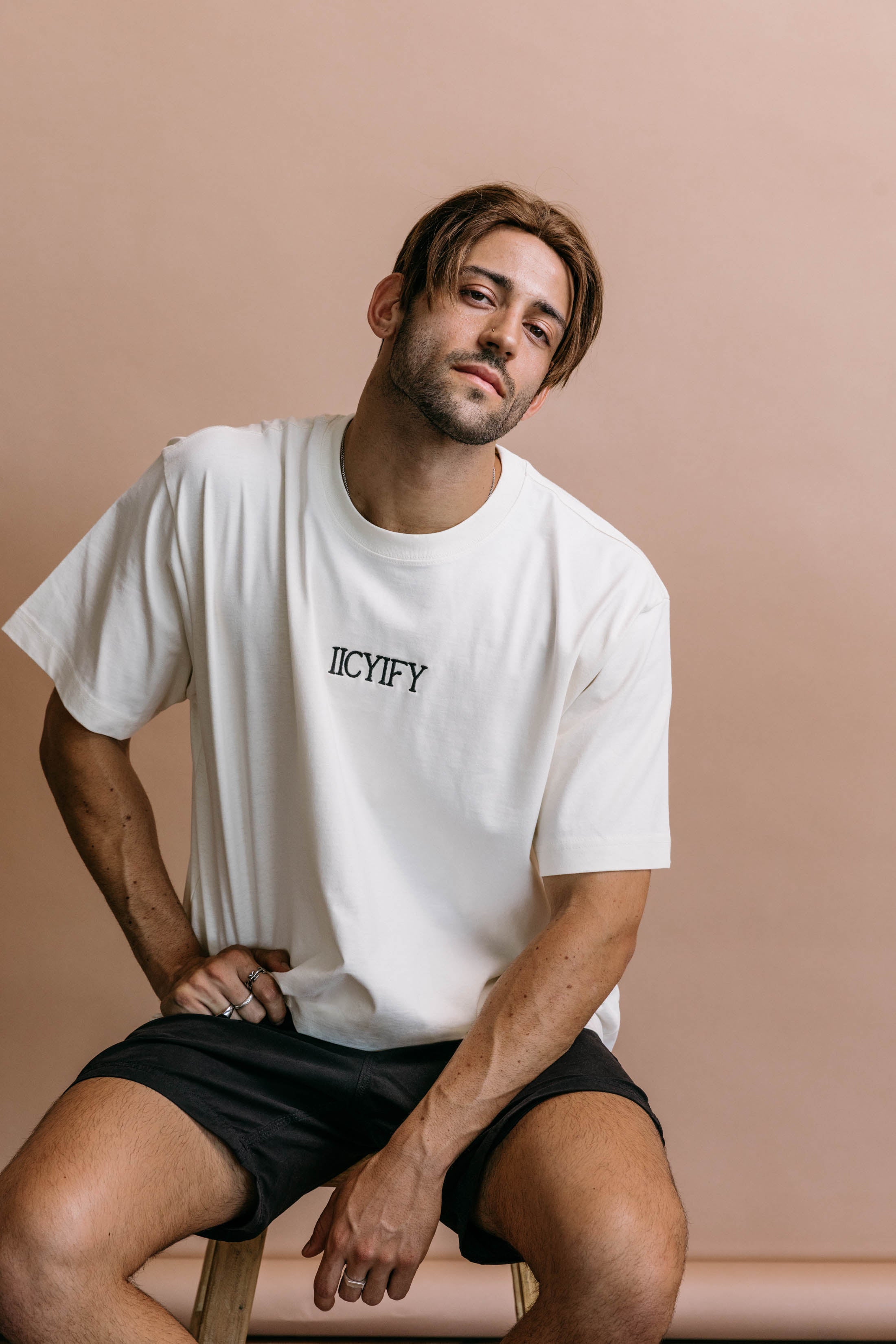 Male model wearing the ecru "Iicyify" relaxed fit embroidered T-shirt by WNGSPN, styled in a minimal, elevated aesthetic.