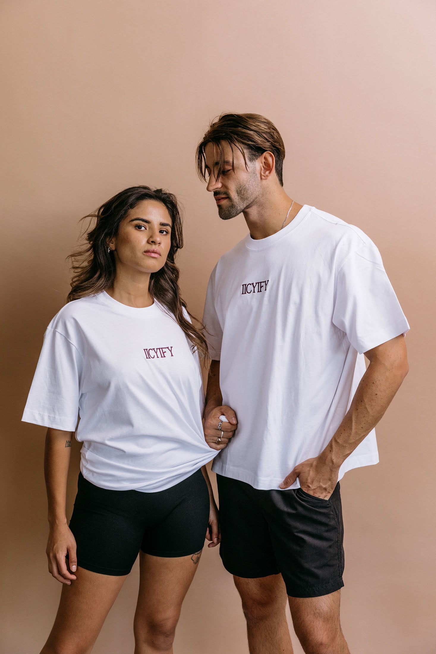 Couple wearing the white "Iicyify" relaxed fit embroidered T-shirt by WNGSPN, with subtle tension and modern edge.