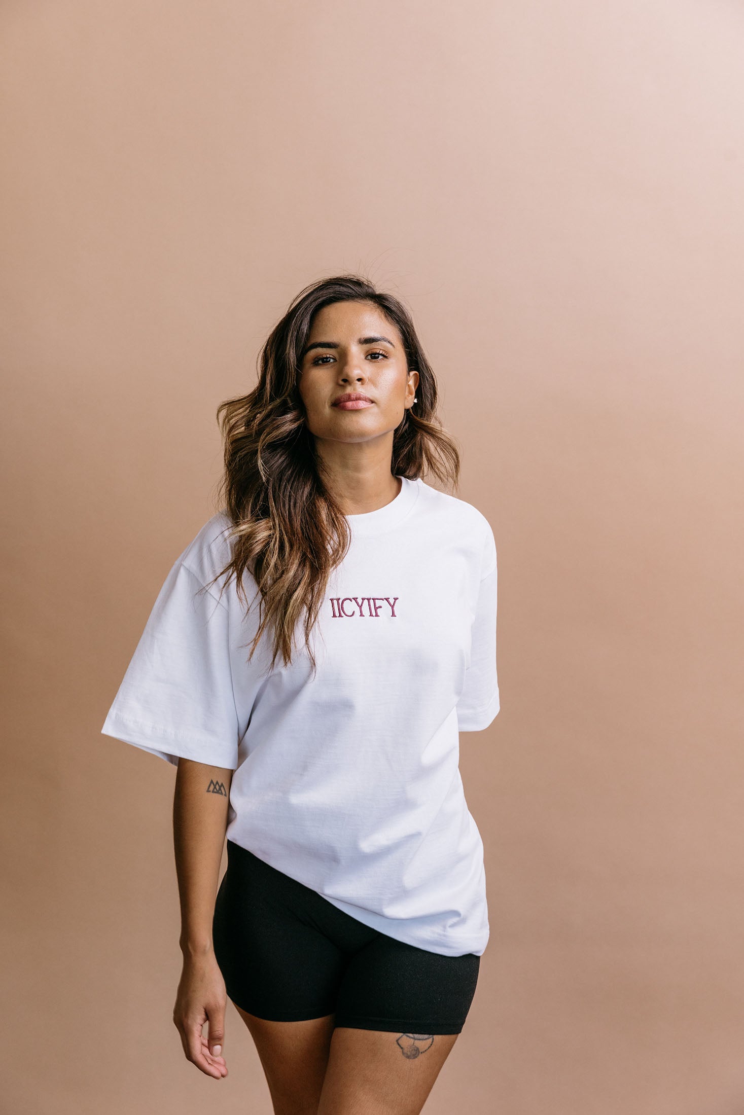 Female model wearing the white "Iicyify" relaxed fit embroidered T-shirt by WNGSPN, with a relaxed silhouette and clean lines.