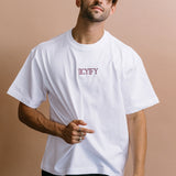 Male model wearing the white "Iicyify" relaxed fit embroidered T-shirt by WNGSPN, with a relaxed silhouette and clean lines.