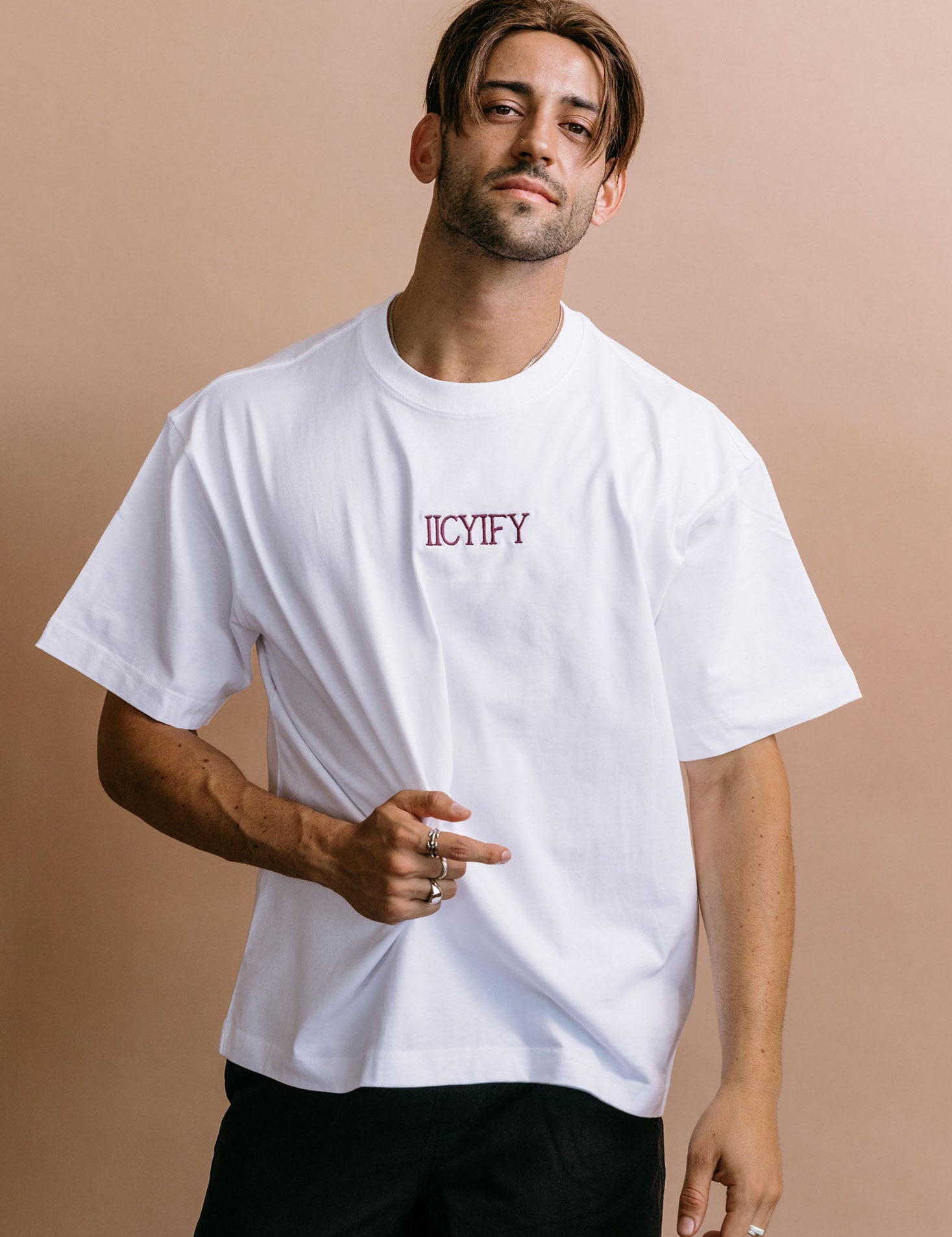 Male model wearing the white "Iicyify" relaxed fit embroidered T-shirt by WNGSPN, with a relaxed silhouette and clean lines.