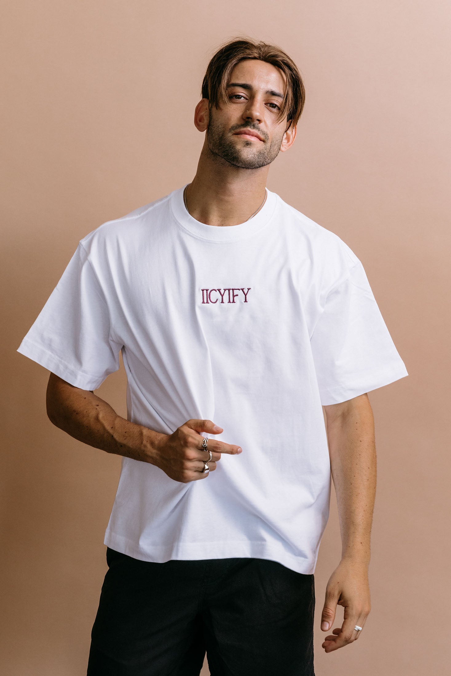 Male model wearing the white "Iicyify" relaxed fit embroidered T-shirt by WNGSPN, with a relaxed silhouette and clean lines.