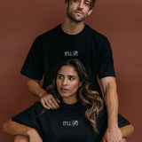 Couple wearing the black "It'll Fit" relaxed fit embroidered T-shirt by WNGSPN, styled as elevated romance reader apparel.
