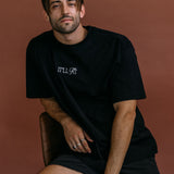 Male model wearing the black "It'll Fit" relaxed fit embroidered T-shirt by WNGSPN, styled with understated confidence.