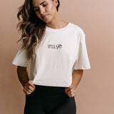 Female model wearing the ecru "It'll Fit" cropped embroidered T-shirt by WNGSPN, with a relaxed silhouette and clean lines.