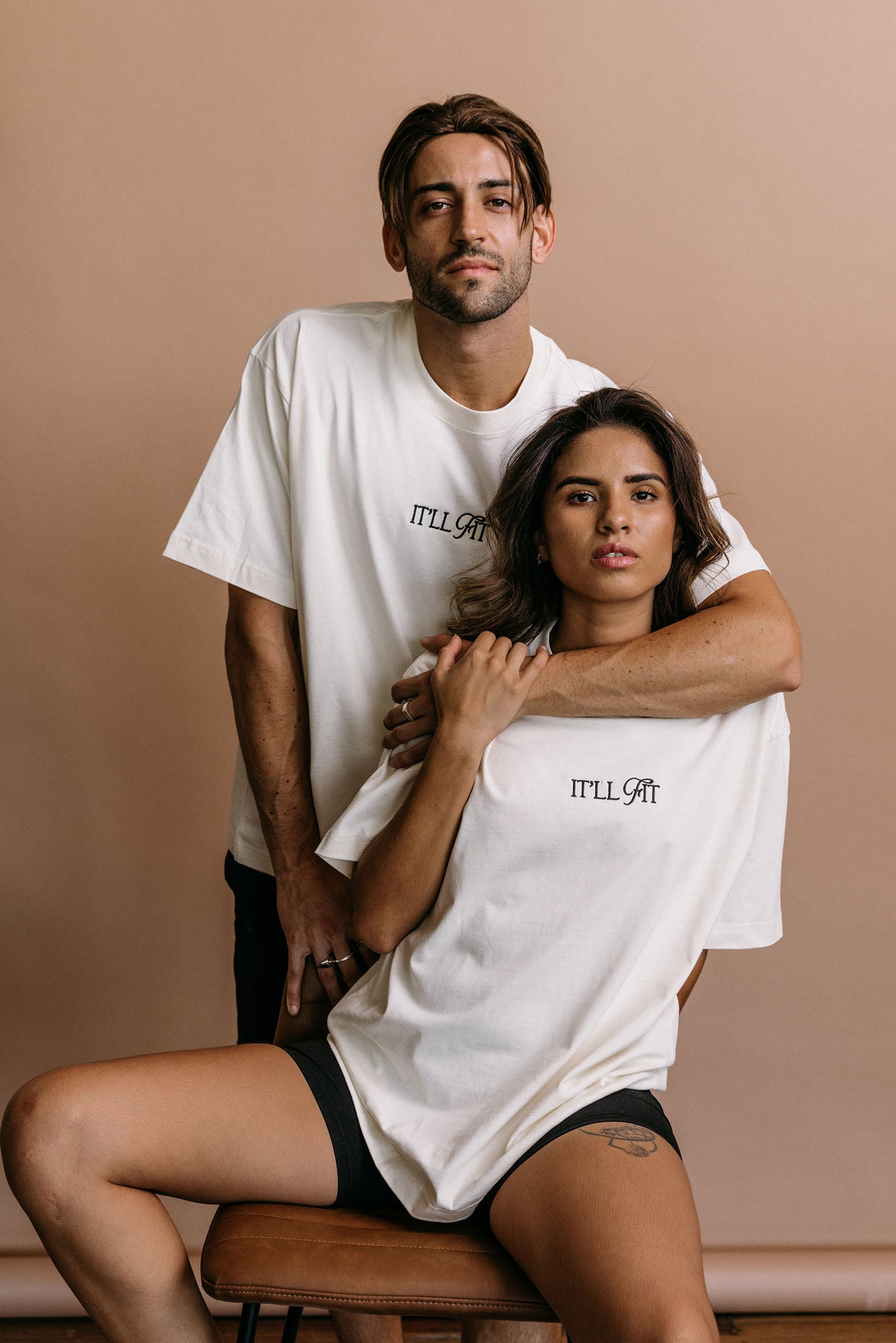 Couple wearing the ecru "It'll Fit" relaxed fit embroidered T-shirt by WNGSPN, capturing a refined bookish aesthetic.
