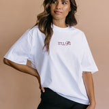 Male model wearing the white "It'll Fit" relaxed fit embroidered T-shirt by WNGSPN, with a relaxed silhouette and clean lines.