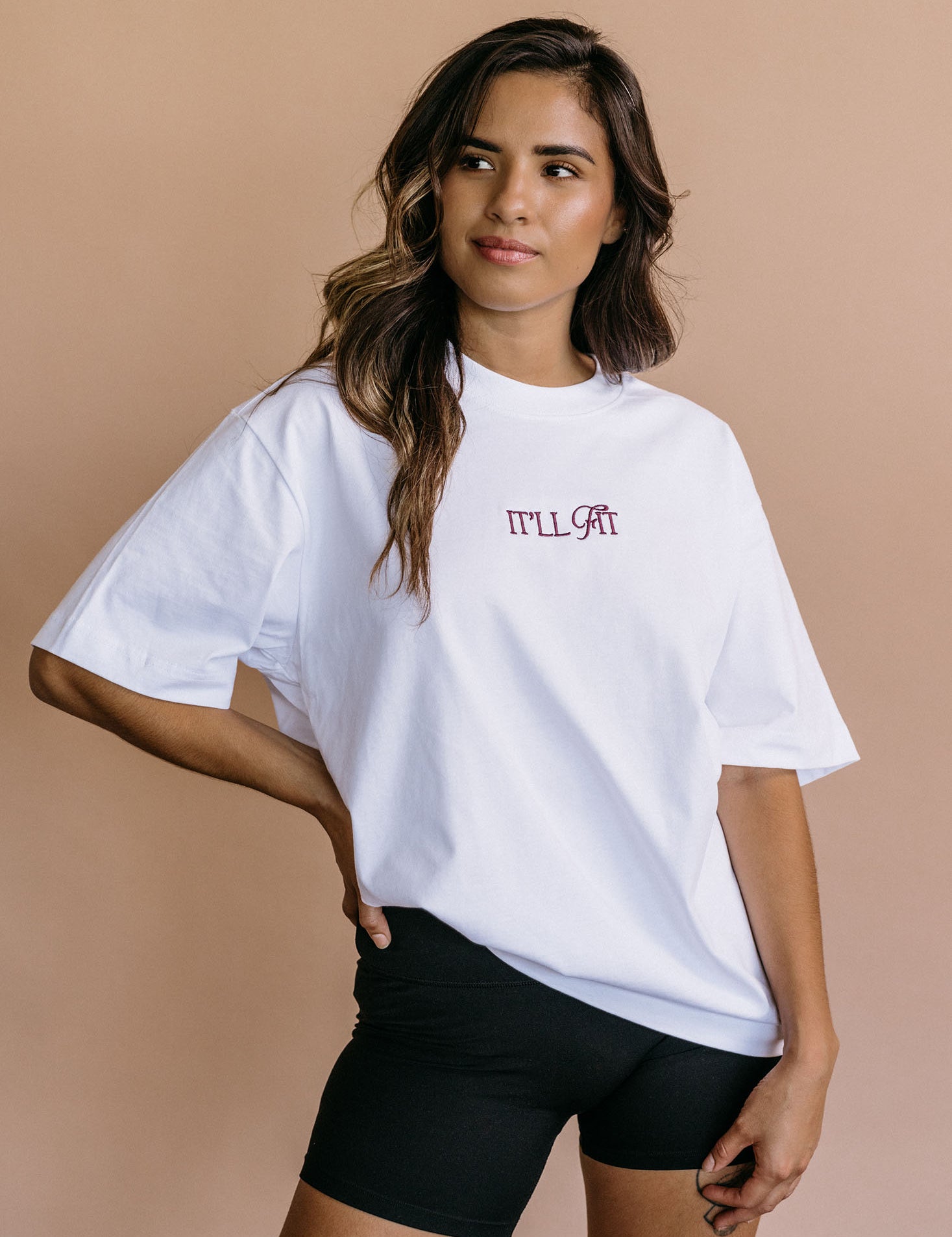 Male model wearing the white "It'll Fit" relaxed fit embroidered T-shirt by WNGSPN, with a relaxed silhouette and clean lines.