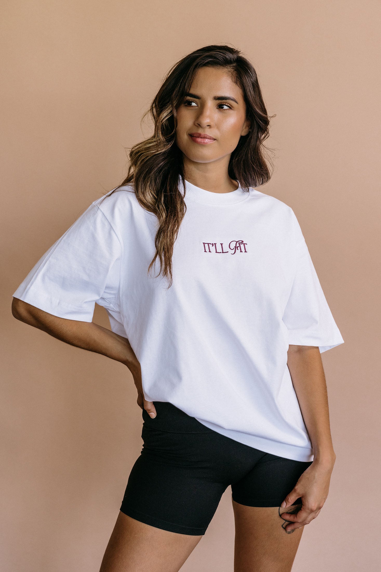Male model wearing the white "It'll Fit" relaxed fit embroidered T-shirt by WNGSPN, with a relaxed silhouette and clean lines.