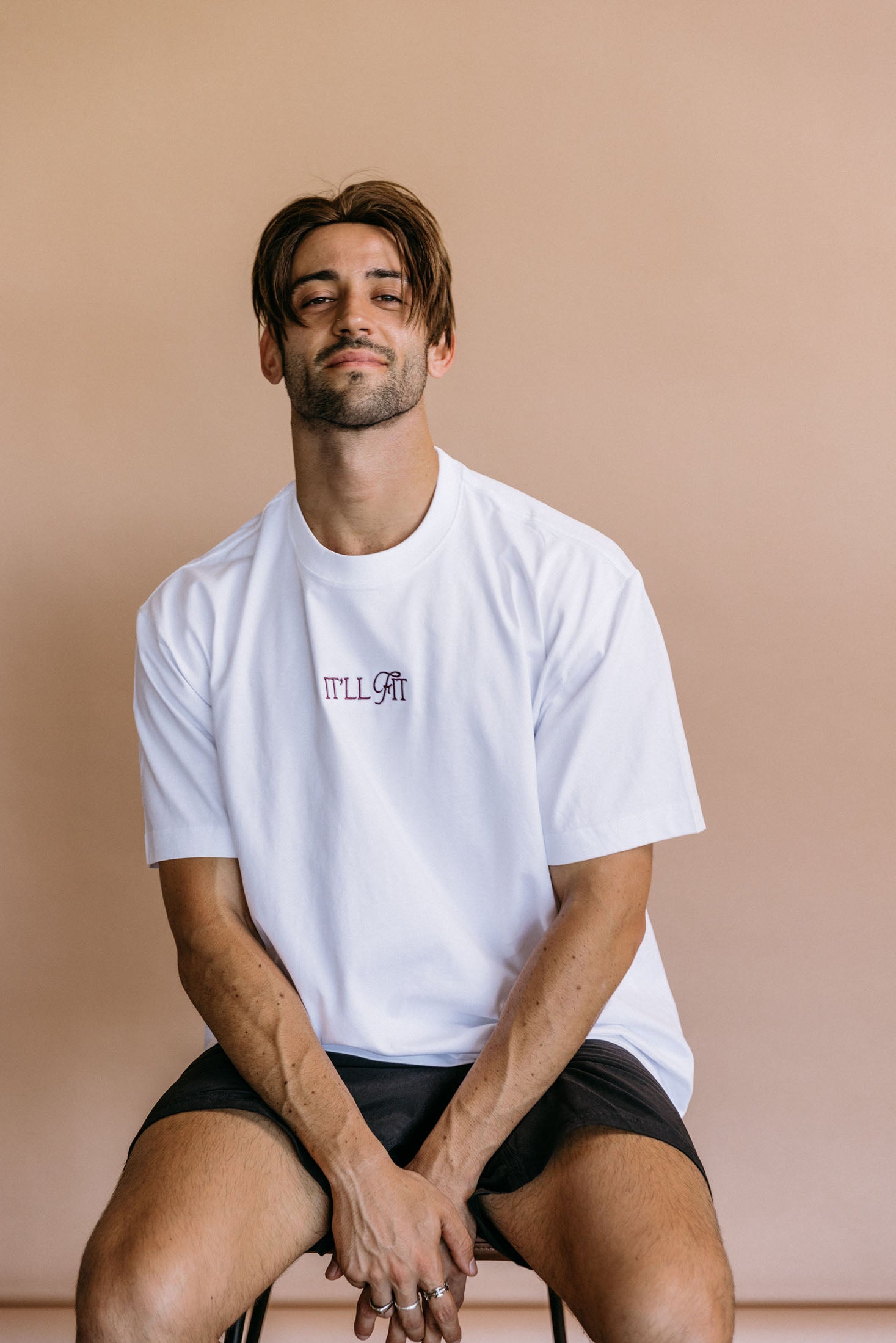 Female model wearing the white "It'll Fit" relaxed fit embroidered T-shirt by WNGSPN, with a relaxed silhouette and clean lines.