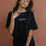 Female model wearing the black "Oh Gods" cropped embroidered T-shirt by WNGSPN, with a relaxed silhouette and clean lines.