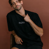 Male model wearing the black "Oh Gods" relaxed fit embroidered T-shirt by WNGSPN, styled with understated confidence.