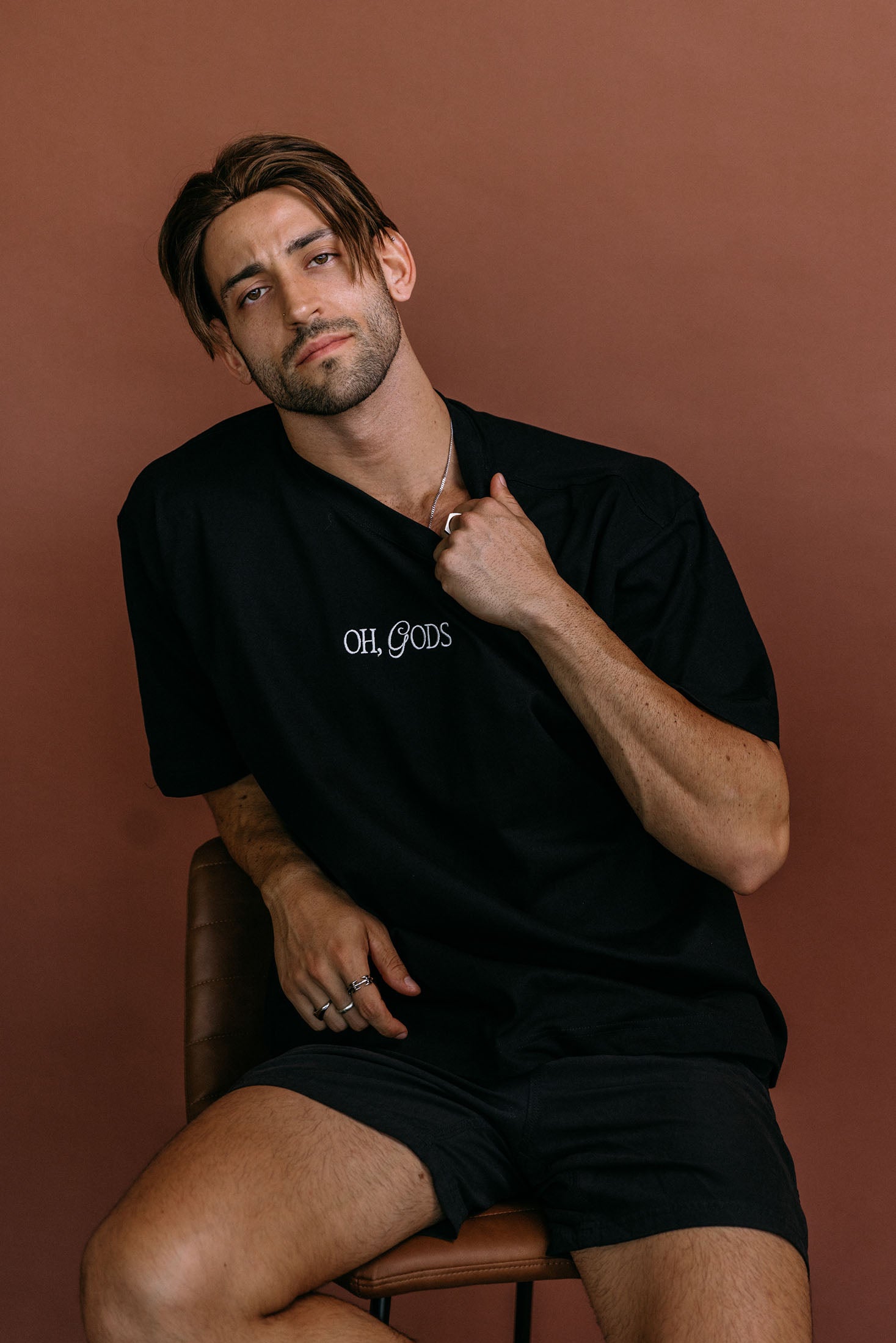 Male model wearing the black "Oh Gods" relaxed fit embroidered T-shirt by WNGSPN, styled with understated confidence.