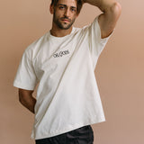 Male model wearing the ecru "Oh Gods" relaxed fit embroidered T-shirt by WNGSPN, styled in a minimal, elevated aesthetic.