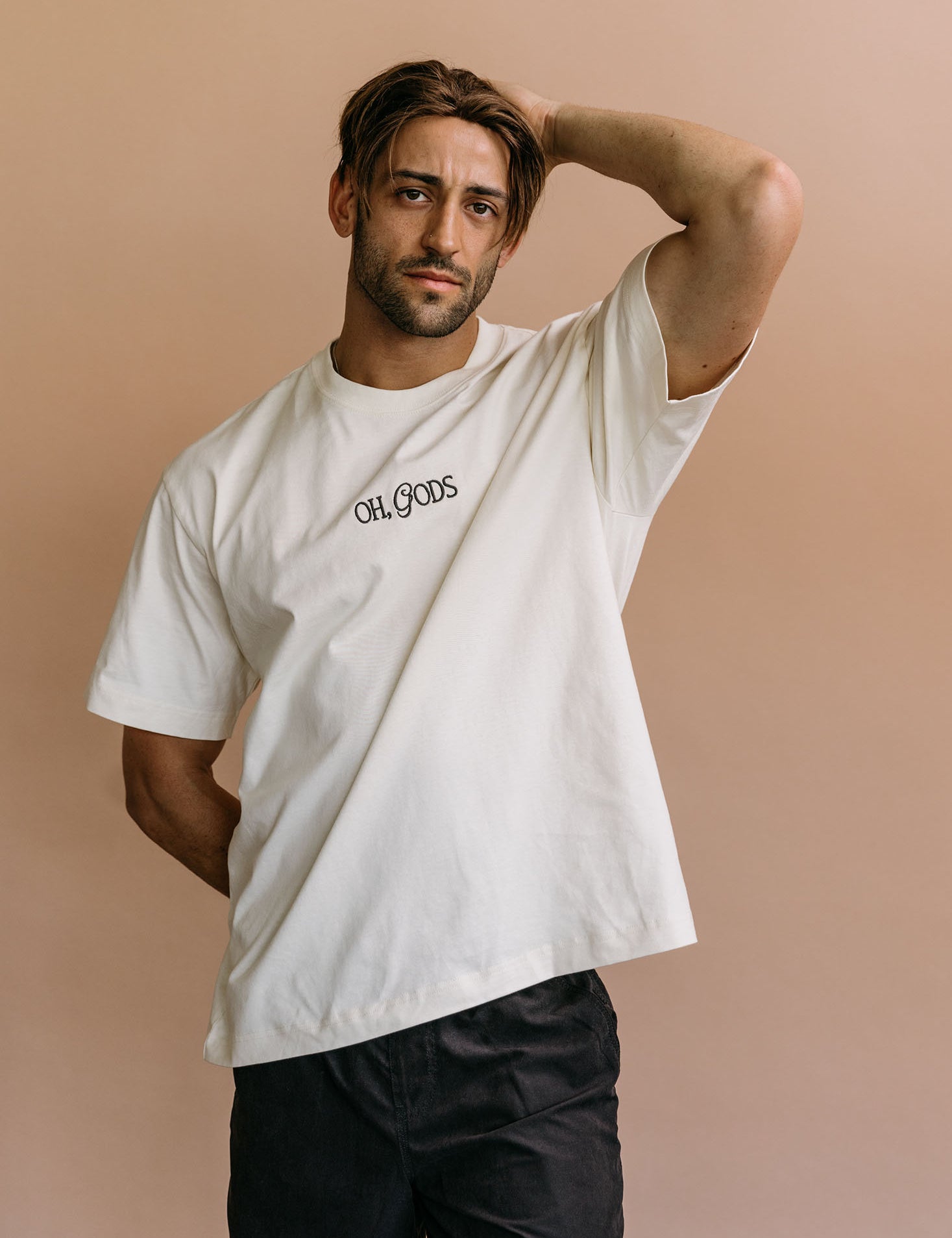 Male model wearing the ecru "Oh Gods" relaxed fit embroidered T-shirt by WNGSPN, styled in a minimal, elevated aesthetic.