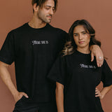 Couple wearing the black "There She Is" relaxed fit embroidered T-shirt by WNGSPN, styled as elevated romance reader apparel.