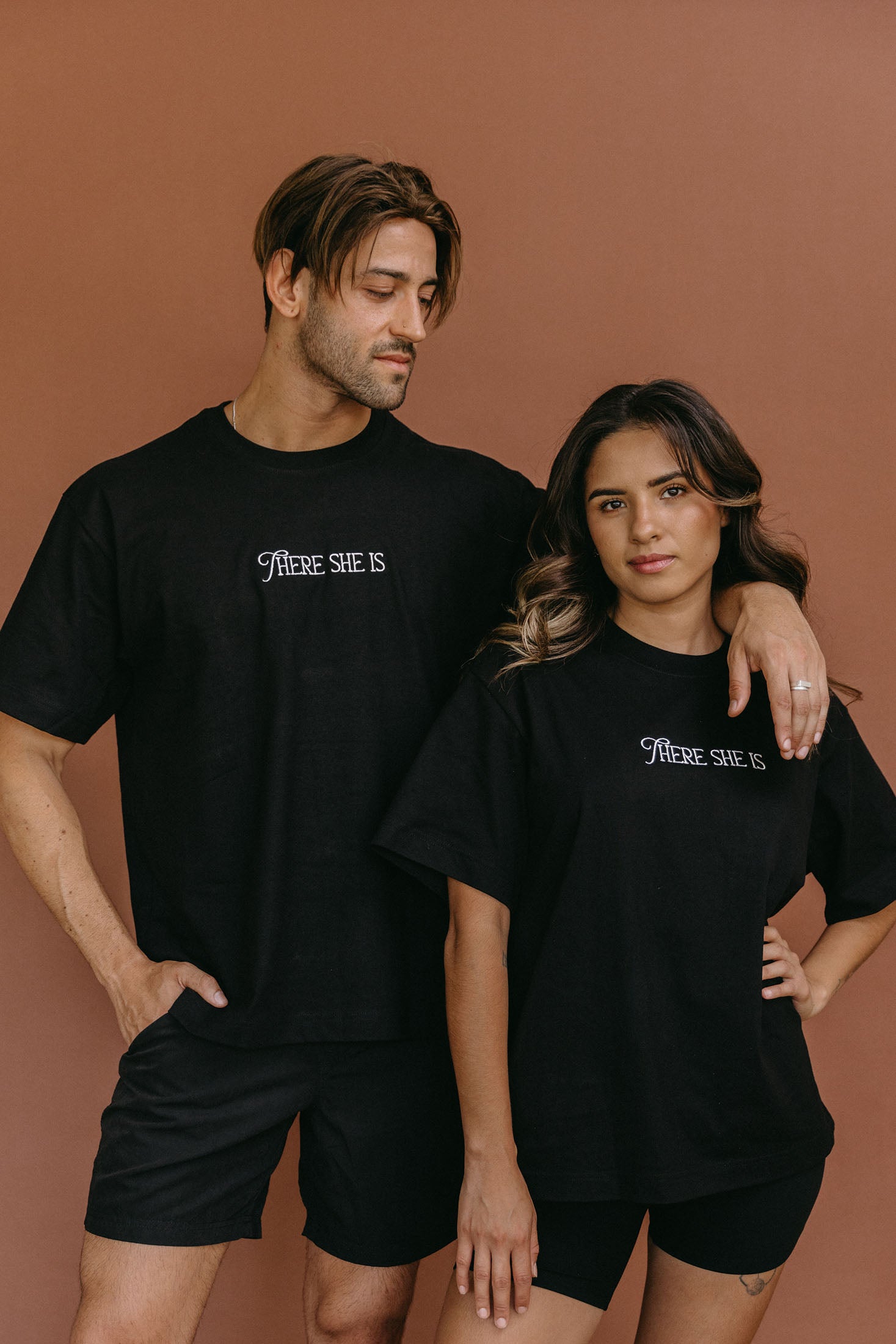 Couple wearing the black "There She Is" relaxed fit embroidered T-shirt by WNGSPN, styled as elevated romance reader apparel.