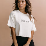 Female model wearing the ecru "There She Is" cropped embroidered T-shirt by WNGSPN, with a relaxed silhouette and clean lines.