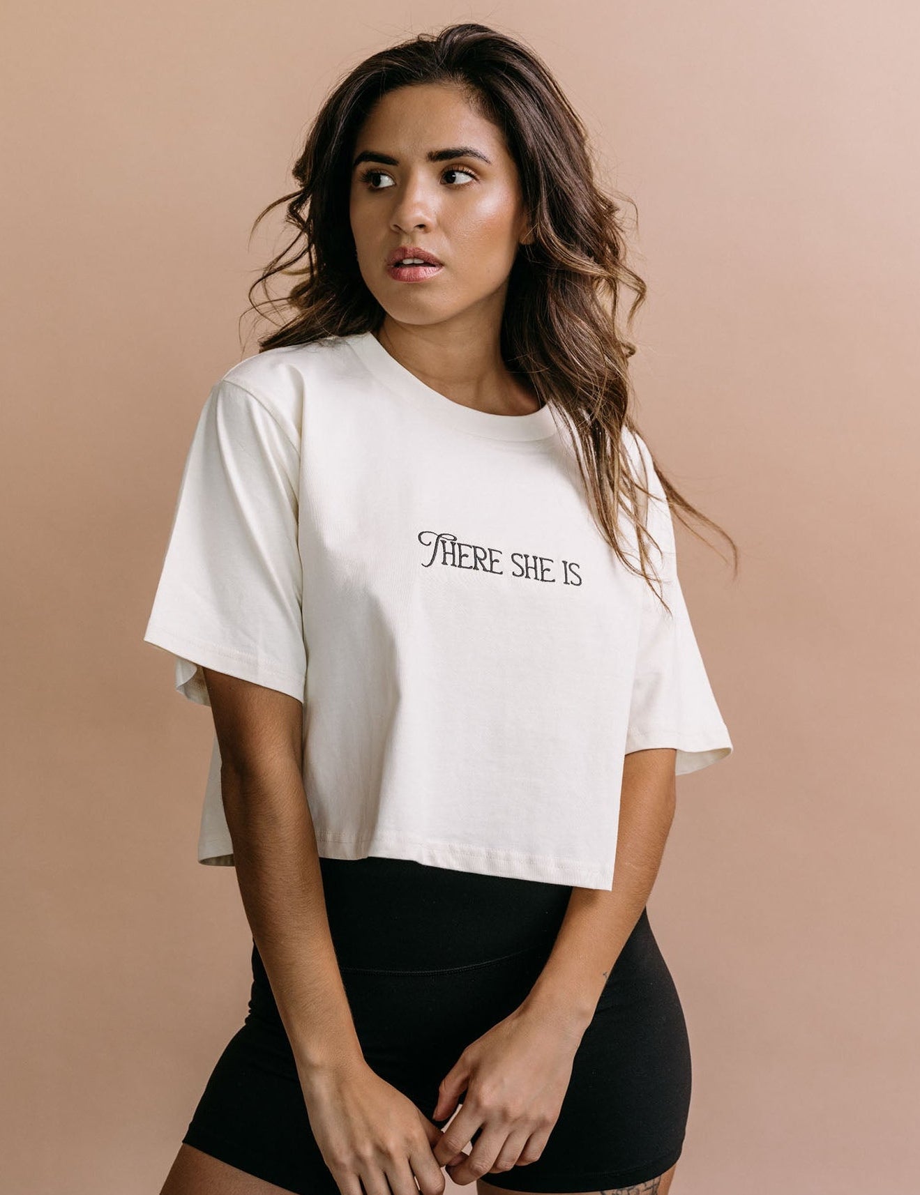 Female model wearing the ecru "There She Is" cropped embroidered T-shirt by WNGSPN, with a relaxed silhouette and clean lines.