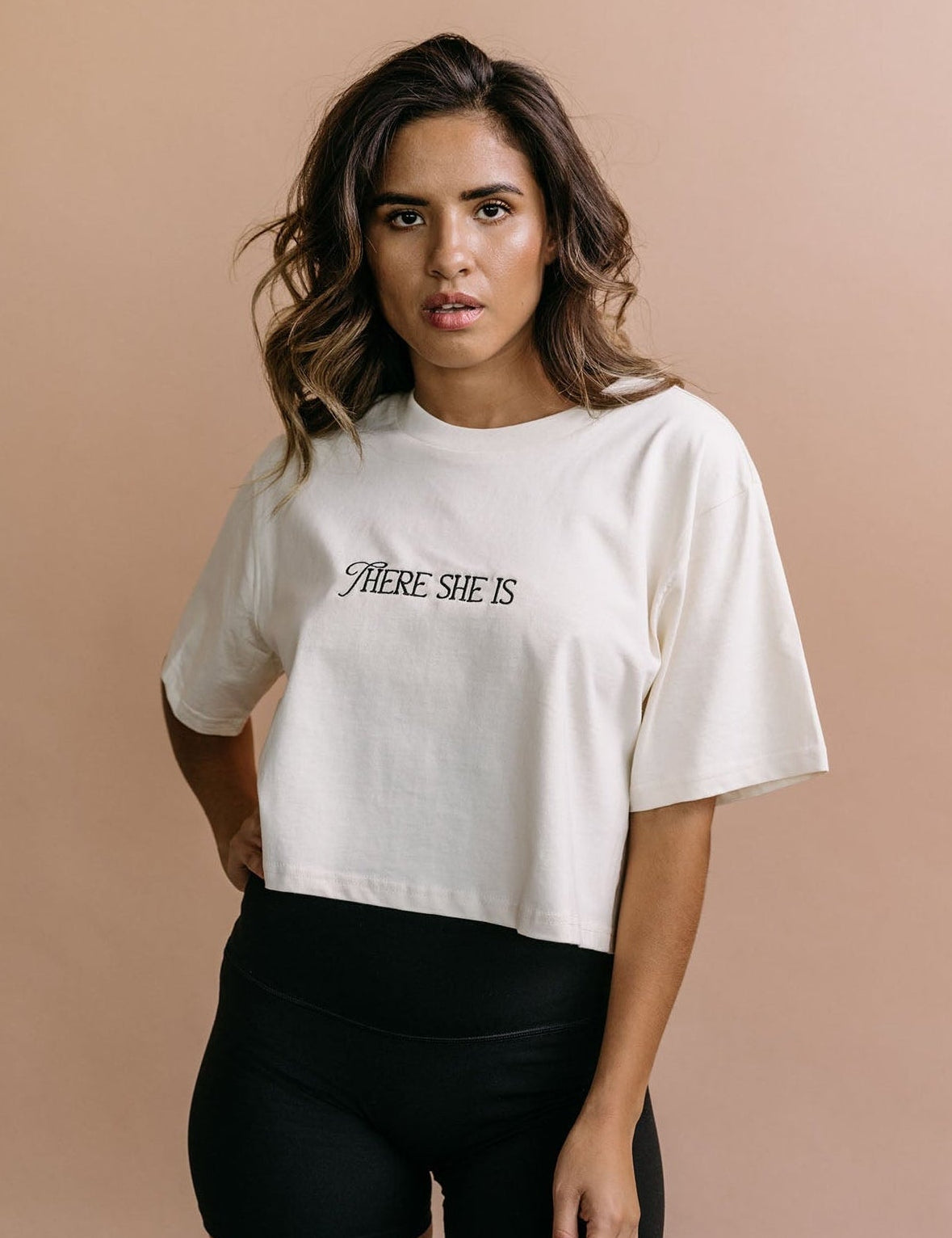 Female model wearing the ecru "There She Is" cropped embroidered T-shirt by WNGSPN, with a relaxed silhouette and clean lines.
