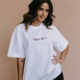 Female model wearing the white "There She Is" relaxed fit embroidered T-shirt by WNGSPN, with a relaxed silhouette and clean lines.