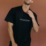 Male model wearing the black "Use Your Words" relaxed fit embroidered T-shirt by WNGSPN, styled with understated confidence.