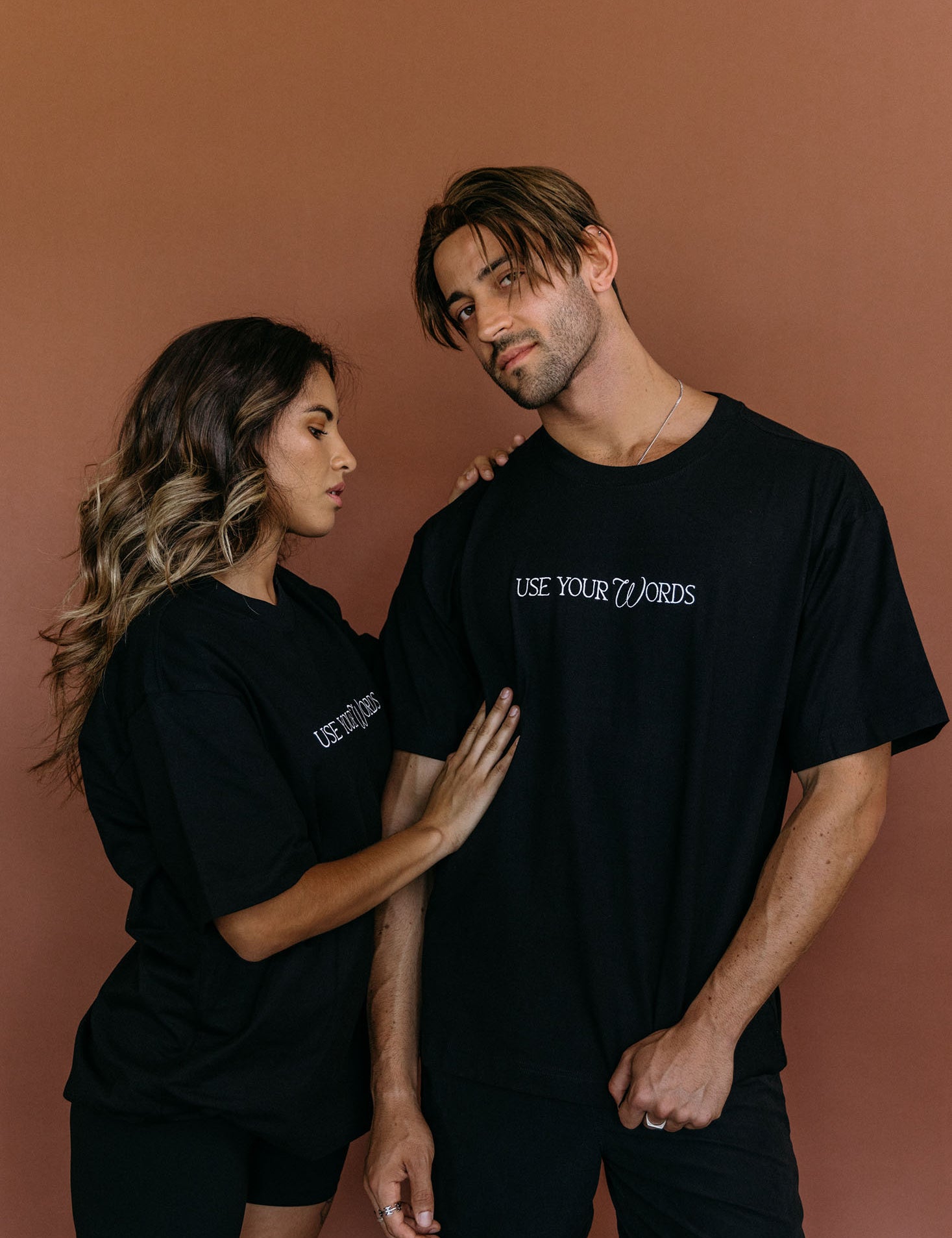 Couple wearing the black "Use Your Words" relaxed fit embroidered T-shirt by WNGSPN, styled as elevated romance reader apparel.